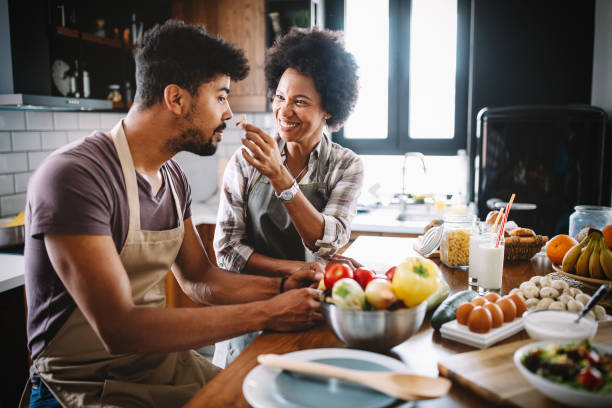 istock Beautiful young couple having fun and laughing while cooking in kitchen 1205235308
