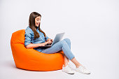 Profile side view of her she nice attractive lovely charming cheerful cheery girl sitting in bag chair using laptop isolated over light white color background