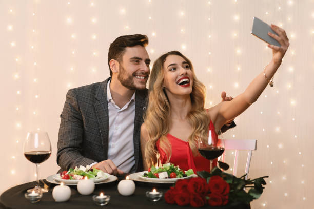 istock Romantic couple using smartphone, to take salfie on date at restaurant 1205236152
