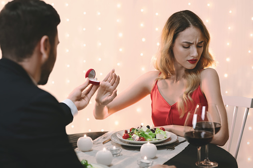 She Said No. Young Woman Refusing Marriage Proposal From Boyfriend, Gesturing Stop To Offered Engagement Ring On Date In Restaurant, Selective Focus