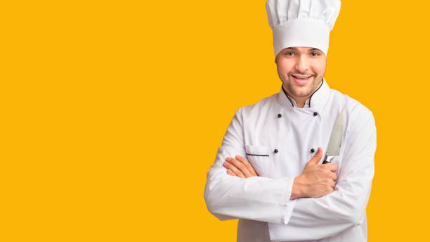 istock Cook Guy Holding Kitchen Knife Standing Over Yellow Background, Panorama 1205237359