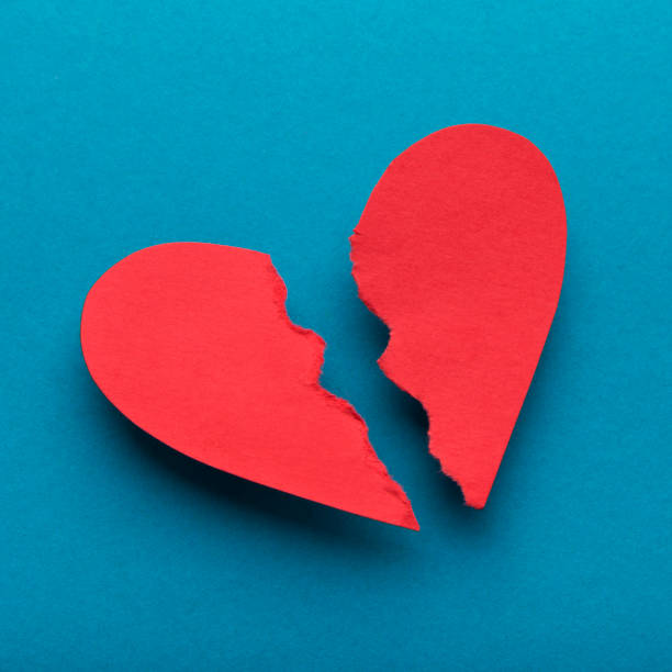 istock Red paper broken heart on bright blue background 1205237380
