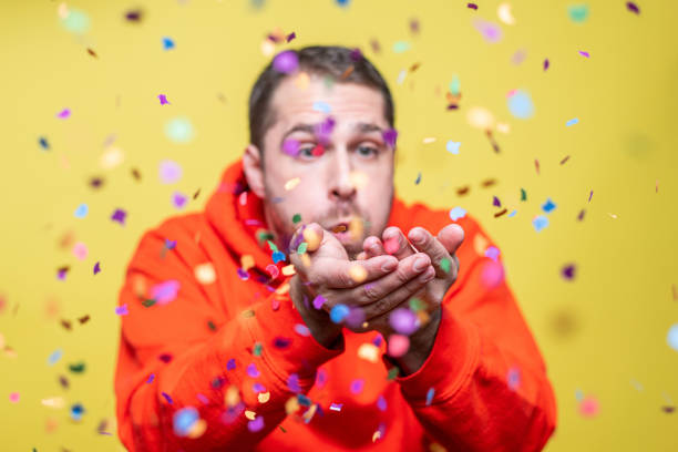 istock man blowing confetti towards the camera 1205237768