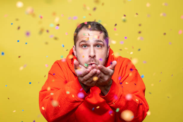 istock man blowing confetti towards the camera 1205237841
