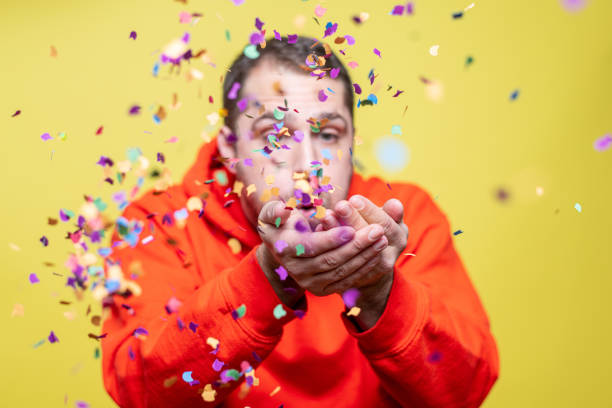 istock man blowing confetti towards the camera 1205237971