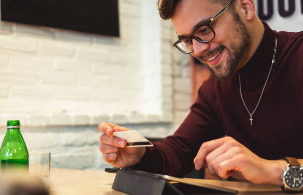 istock Young smiling man holding credit card and typing on Digital Tablet 1205239897