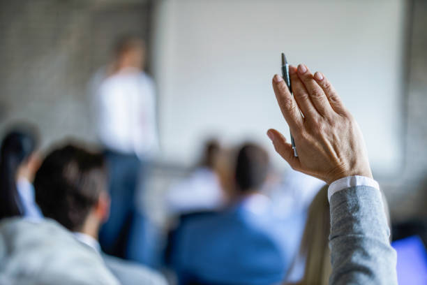Close up of businesswoman raising her hand on a seminar in board room. Close up of unrecognizable businesswoman raising her hand to ask the question on a seminar in board room. hand raised stock pictures, royalty-free photos & images