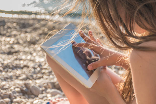 istock Content Girl on Summer Holiday Relaxing Using Digital Tablet on the Beach 1205240971