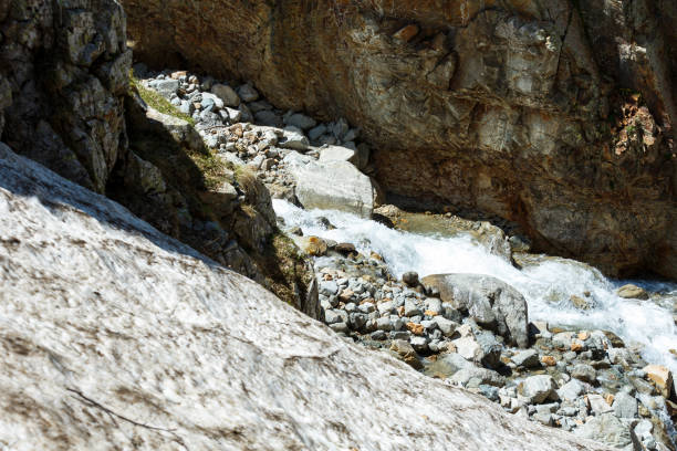 A river runs in mountain, deep valley with steep banks, rocky stream bed