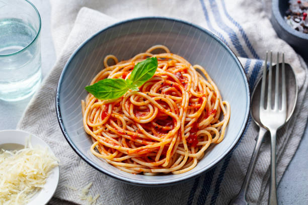 Pasta, spaghetti with tomato sauce and fresh basil in a bowl. Close up.