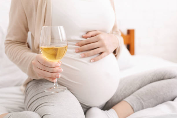 femme enceinte retenant le verre de vin blanc - abdomen addiction adult alcohol photos et images de collection