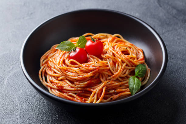 istock Pasta, spaghetti with tomato sauce in black bowl. Grey stone background. Close up. 1205243017