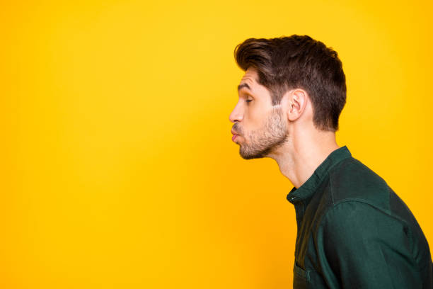 side profile photo of tender man full of feelings pouting his lips to kiss empty space next to him with eyes closed in a fit of imaginary dreams isolated vibrant color background - beijar imagens e fotografias de stock