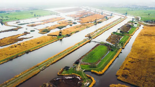 Drone panoramic photo of beautiful old windmills staying on the field with river and canals in Netherlands