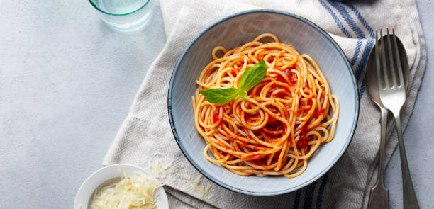 pasta, spaghetti mit tomatensauce und frisches basilikum in einer schüssel. grauer hintergrund. ansicht von oben. kopieren sie den speicherplatz. - tomatensoße stock-fotos und bilder