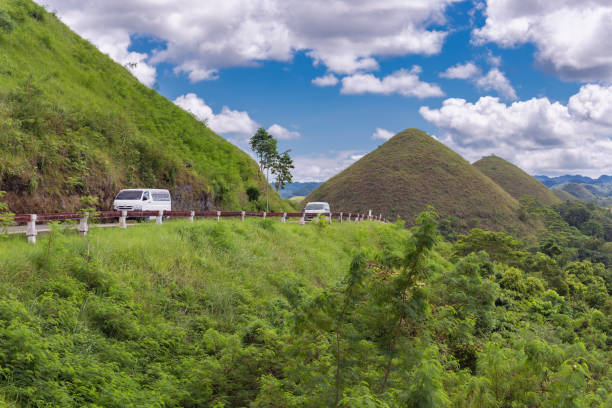 Road with cars to the Chocolate Hills Bohol, Philippines - January, 27, 2020: Road with cars to the Chocolate Hills chocolate hills photos stock pictures, royalty-free photos & images