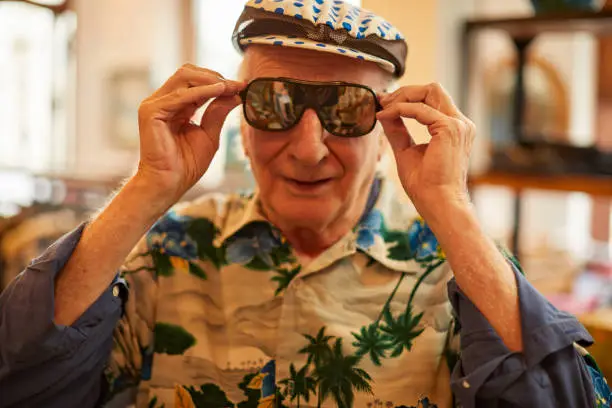 Photo of An eccentric senior man tries on a pair of sunglasses.
