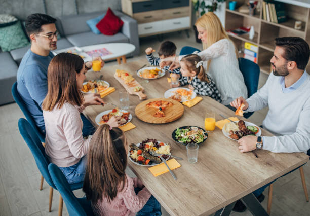 istock Two young married couples and friends with children at the dining table 1205247046
