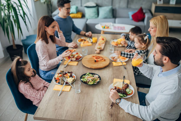 istock Two married couples and friends with children at the dining table 1205247095