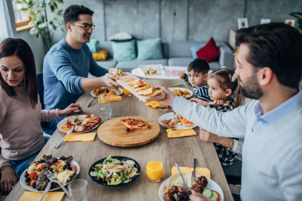 istock Two happy married couples and friends with children at the dining table 1205247162
