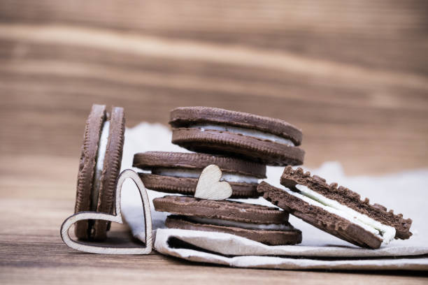 chocolate chip cookie sandwich on kraft paper on a wooden background. Wooden hearts. Happy Valentine's day. beautiful picture with biscuits. texture. chocolate chip cookie sandwich on kraft paper on a wooden background. Wooden hearts. Happy Valentine's day. beautiful picture with biscuits. texture. round sugar cookie stock pictures, royalty-free photos & images