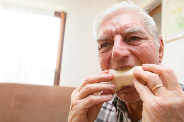 istock Senior Man Eating Fruit in Domestic Room 1205247539