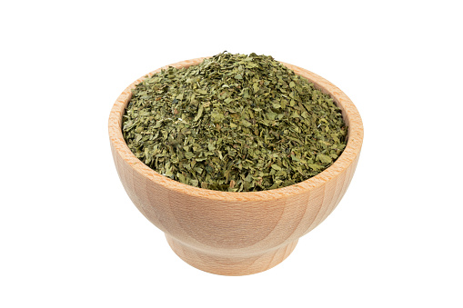 dried lovage herb in wooden bowl isolated on white background. spices and food ingredients