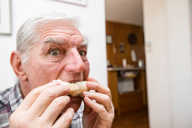 istock Senior Man Eating Fruit and Looking at Camera 1205248052