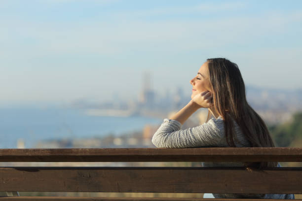 istock Relaxed woman sitting in a bench with closed eyes 1205252171