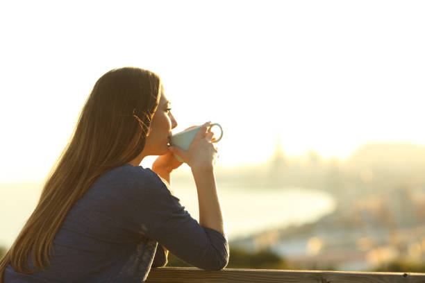 istock Girl drinking coffee contemplating views at sunset 1205252303