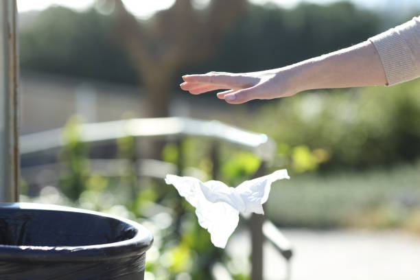 istock Hand throwing litter outside a bin in a park 1205252418