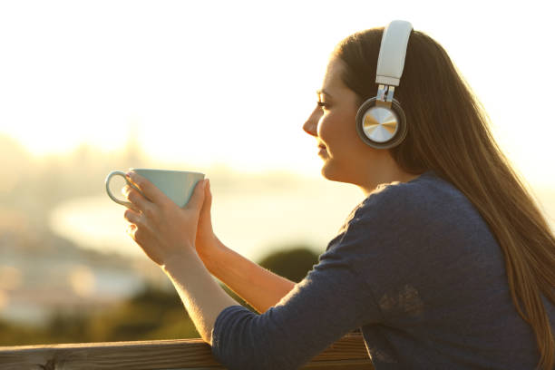 fille détendant avec une cuvette de café écoutant la musique regardant loin - the thinker audio photos et images de collection
