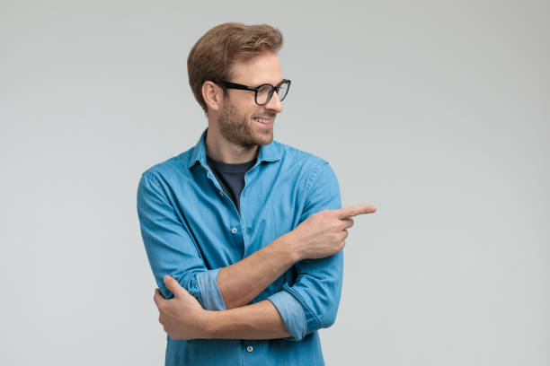 istock happy young casual man looking to side and pointing finger 1205252530