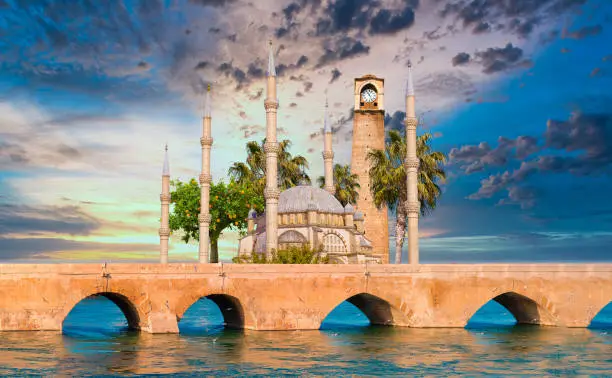 Photo of Sabanci Central Mosque, Old Clock Tower and Stone Bridge in Adana, city of Turkey. Adana City with mosque minarets in front of Seyhan river.