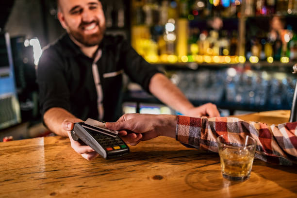 istock Man paying with mobile phone in bar 1205254326