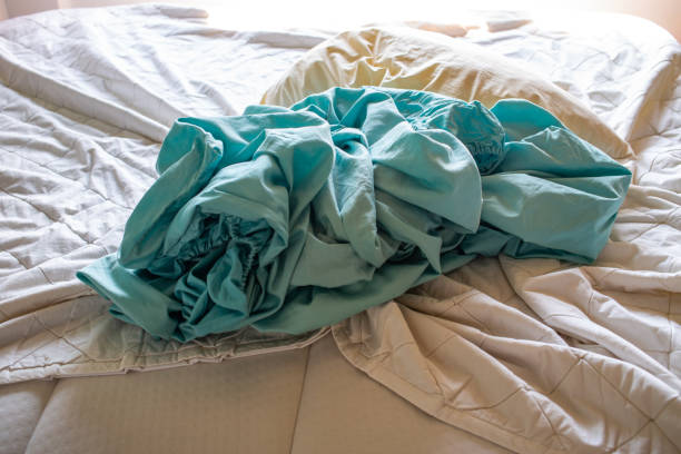 istock Laundry, Used ivory pillow, Used turquoise crumpled bed sheet on white bed, Selective focus, Bedroom cleaning concept 1205254397