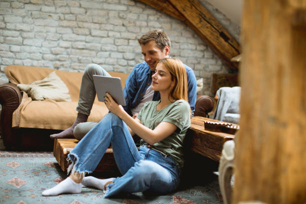 istock Happy couple using digital tablet while sitting  together oh the floor 1205255612