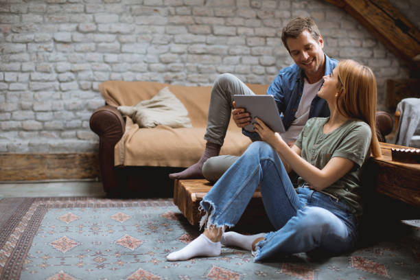 istock Happy couple using digital tablet while sitting  together oh the floor 1205255615