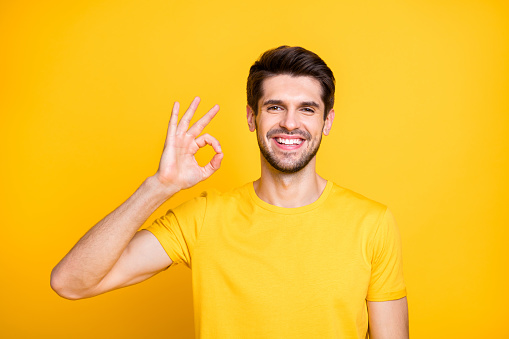 Photo of amazing handsome guy showing okey symbol advising buyer cool quality, product expressing agreement wear casual t-shirt isolated yellow color background