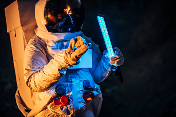 istock Astronaut with blue light lamp exploring rocks dark planet alone 1205255895