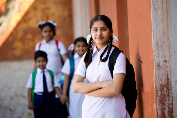 School children at campus Schoolboy and schoolgirl standing outside school with bookbags schoolgirl stock pictures, royalty-free photos & images