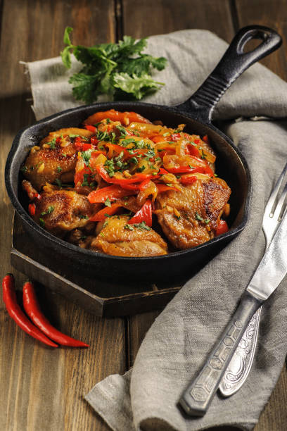 istock Fried chicken in spicy sauce with vegetables. Cooked in a cast iron pan. 1205257009