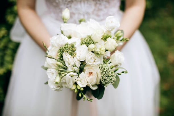 istock bride holding a beautifuk wedding bouquet with white roses 1205257095