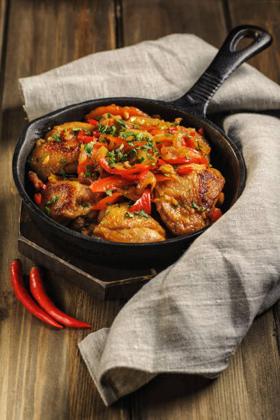 istock Fried chicken in spicy sauce with vegetables. Cooked in a cast iron pan. 1205257150