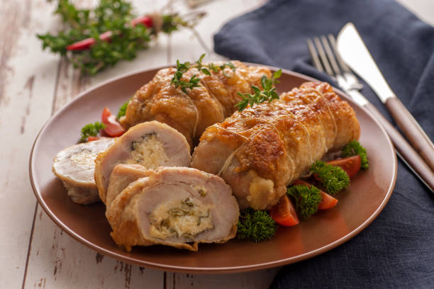Stuffed chicken roll s vegetable garnish and herbs. Stuffed chicken roll s vegetable garnish and herbs. Pieces of roll cut off and lie next to a large piece of meat. Large portion on a plate. Country style. Close up and horizontal orientation. chicken breast photos stock pictures, royalty-free photos & images