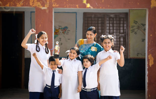 Teacher with students celebrating success Cheerful school teacher with students holding trophy and celebrating victory cheering group of people success looking at camera stock pictures, royalty-free photos & images