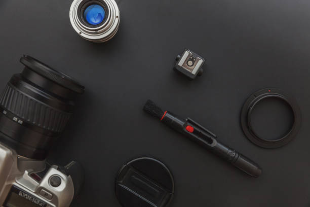 istock Photographer workplace with dslr camera system, camera cleaning kit, lens and camera accessory on dark black table background. Hobby travel photography concept Flat lay top view copy space 1205259637