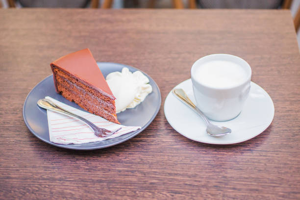 istock Classic Viennese coffee. Dessert with chocolate cake with whipped cream on a plate with a spoon and a fork. Black cappuccino and whipped cream.  Milk in cappuccino. Freshly delicious cake. Hot coffee 1205259833