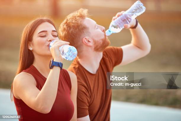 Modern Couple Making Pause In An Urban Park During Jogging Exercise Stock Photo - Download Image Now