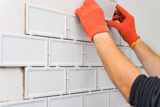 istock Worker is tiling the white tiles on the kitchen wall. Concept of a kitchen renovation. 1205264249